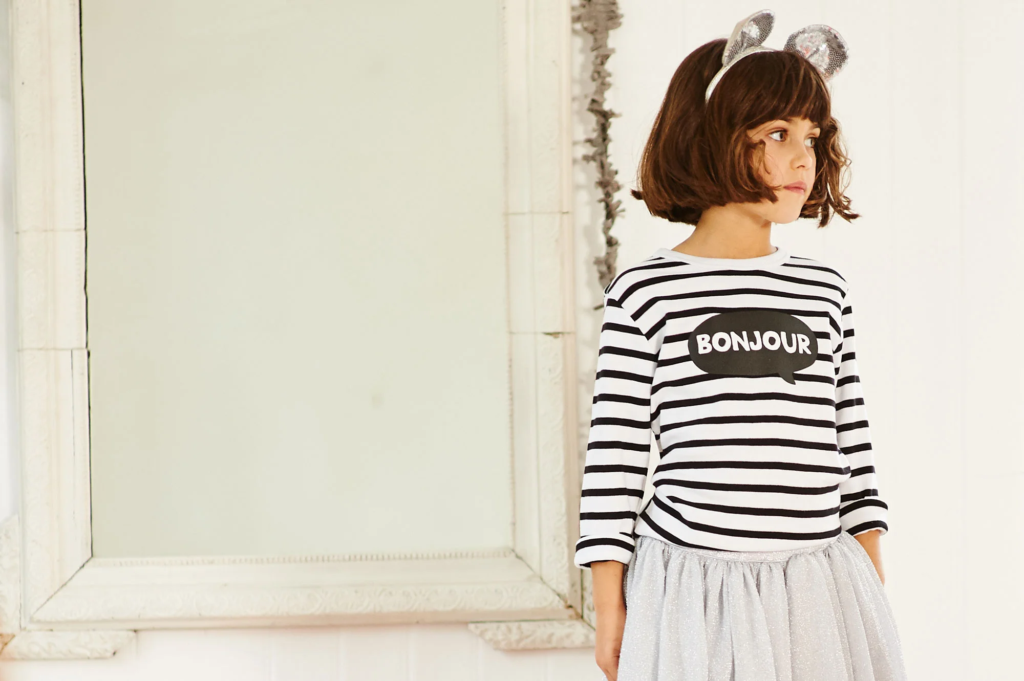a girl wears a Bob & Blossom long-sleeved striped t-shirt with a Bonjour graphic designed by Petits Papiers